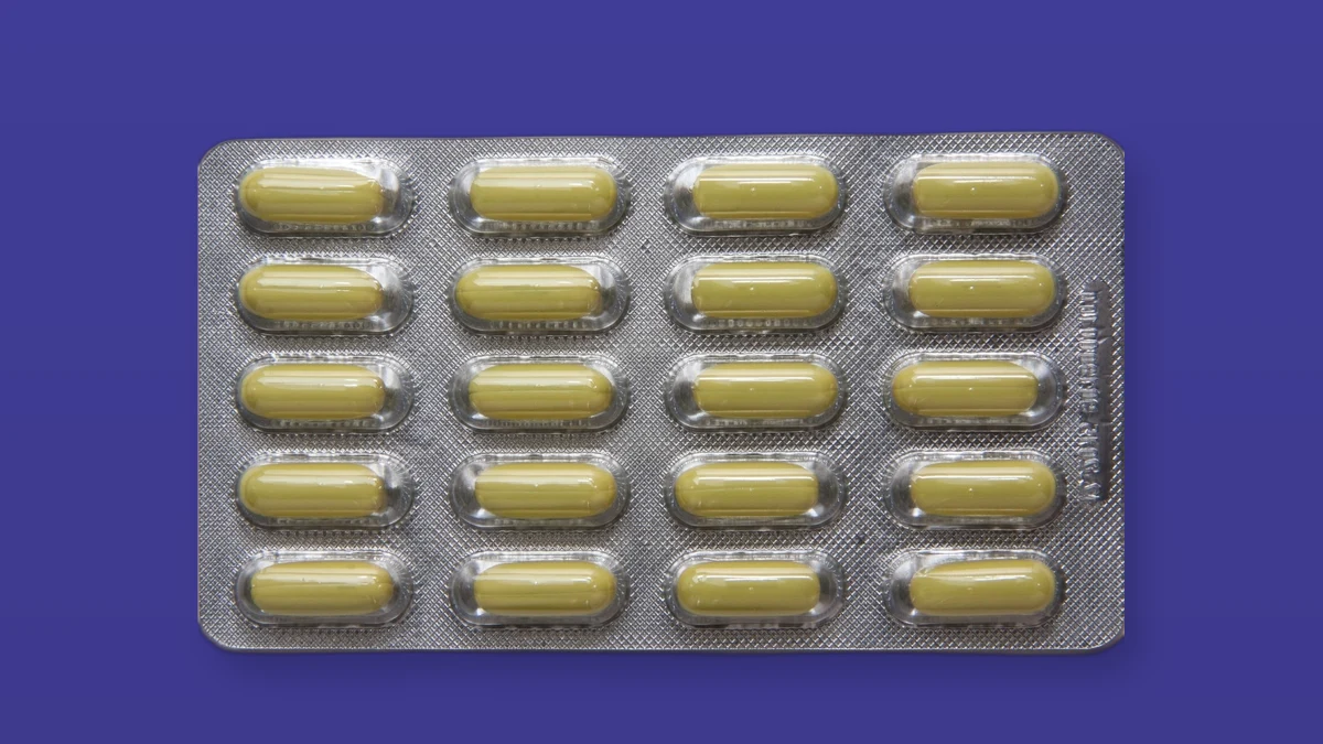 A blister pack of capsule pills photographed on a deep violet background