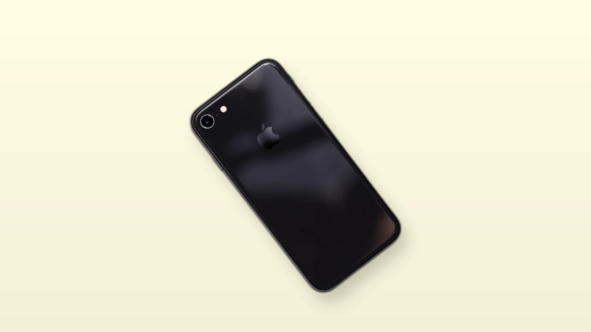A black smartphone photographed on a warm cream background