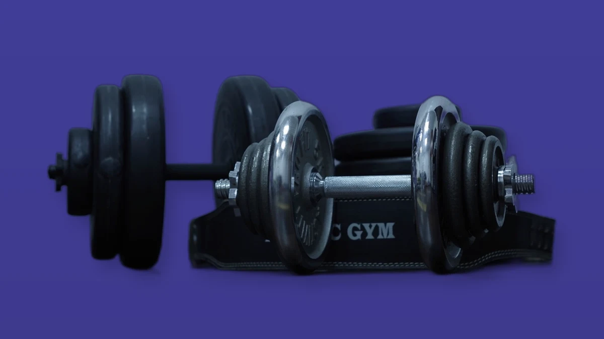 A set of dumbbells and weight plates on a violet background, photo illustration