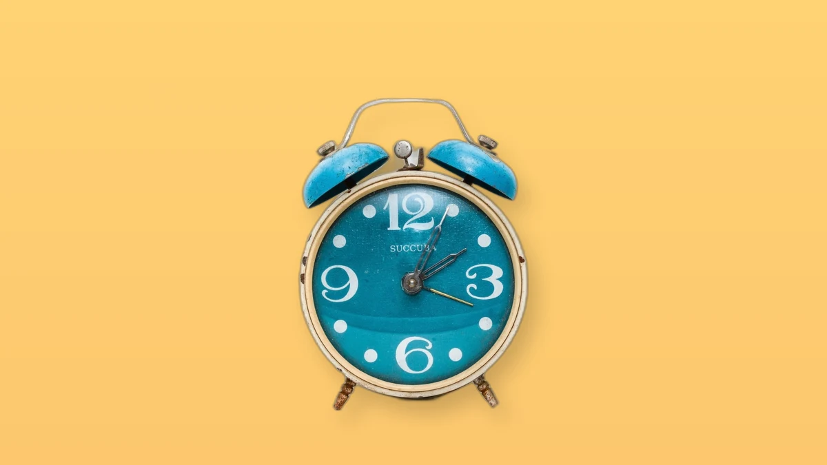 Photo illustration of a blue vintage alarm clock on a peach background