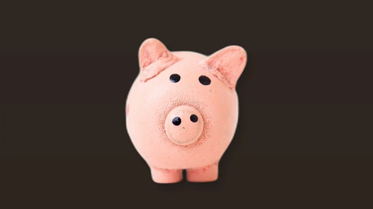 A pink ceramic piggy bank on a dark brown background