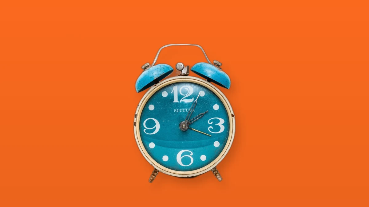 Photo illustration of a blue twin-bell alarm clock on an orange background