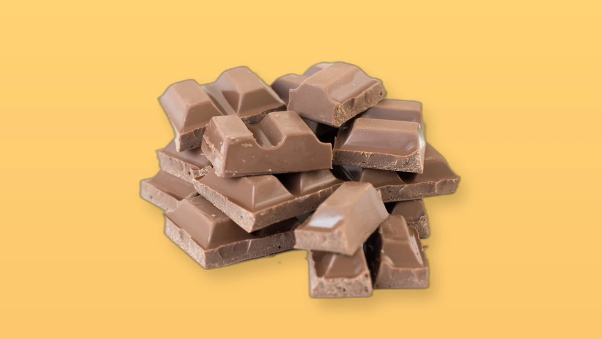 A pile of chocolate pieces on a peach background representing a tempting treat