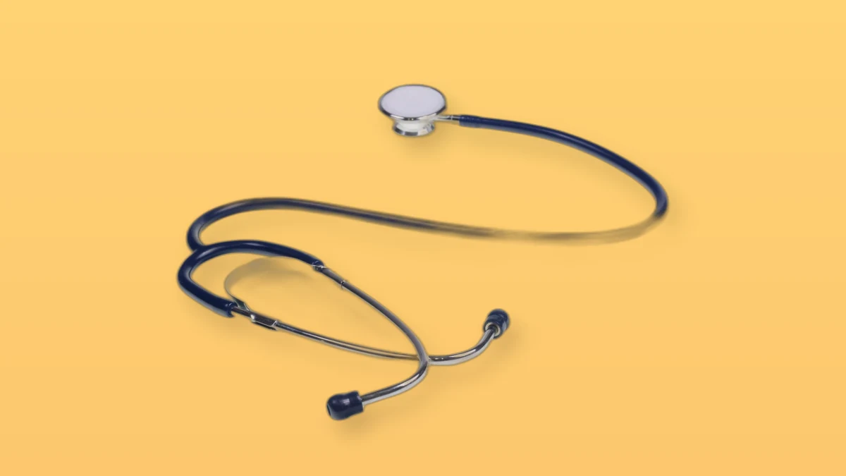 A navy blue stethoscope arranged on a warm peach background