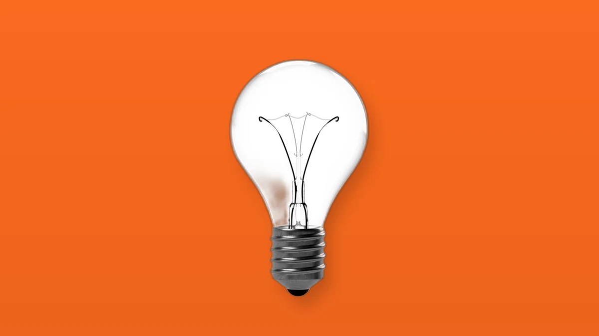Photo illustration of a clear incandescent light bulb on a bright orange background