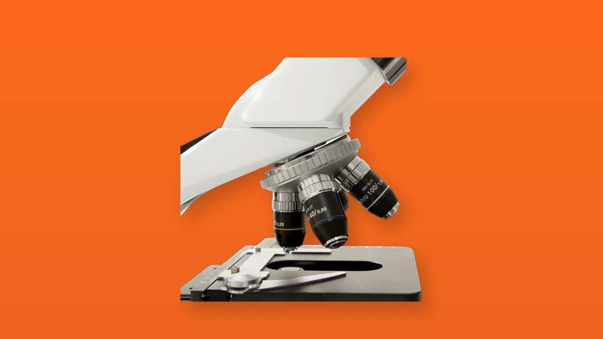 A laboratory microscope isolated on an orange background