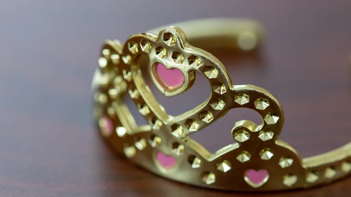 A gold tiara decorated with small pink hearts in close-up