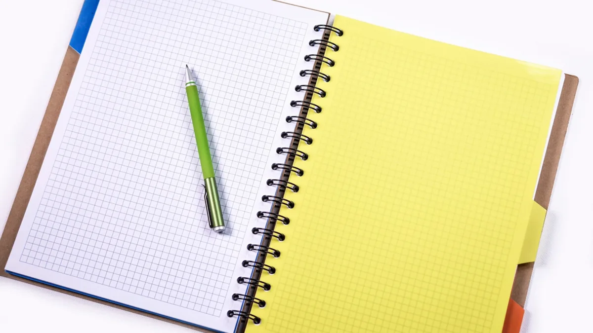 An open grid notebook with a green pen on a clean white background
