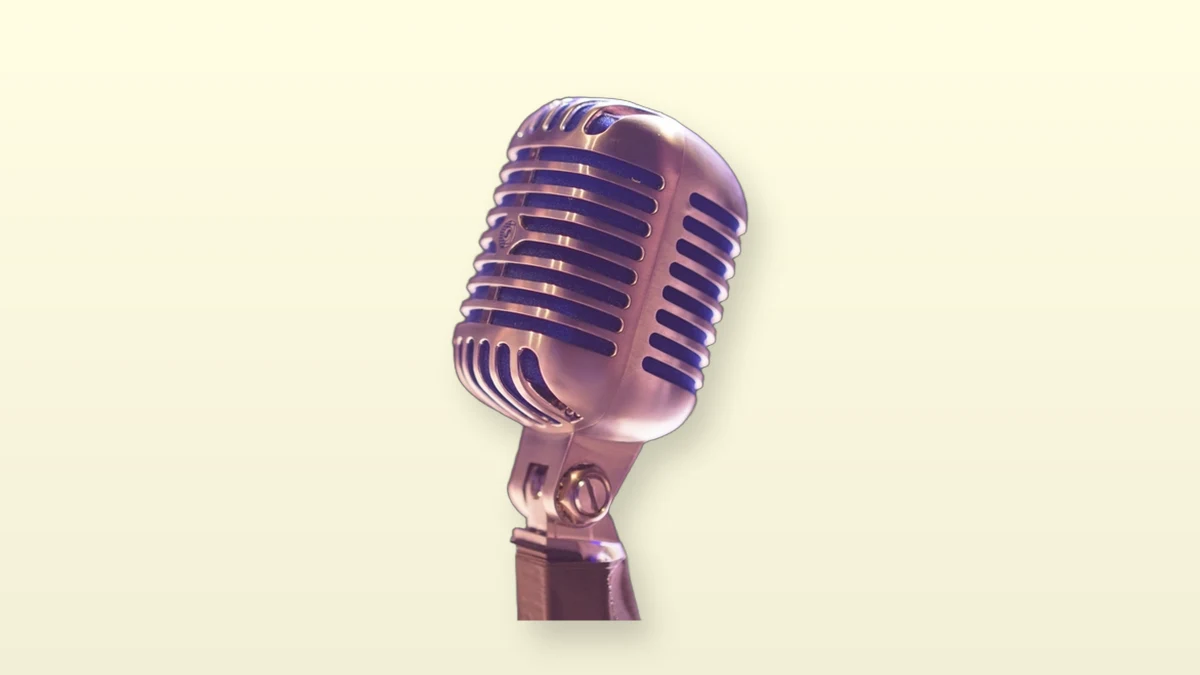 A vintage silver microphone isolated on a warm cream background