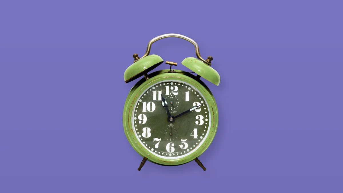 Green vintage alarm clock on a lavender background