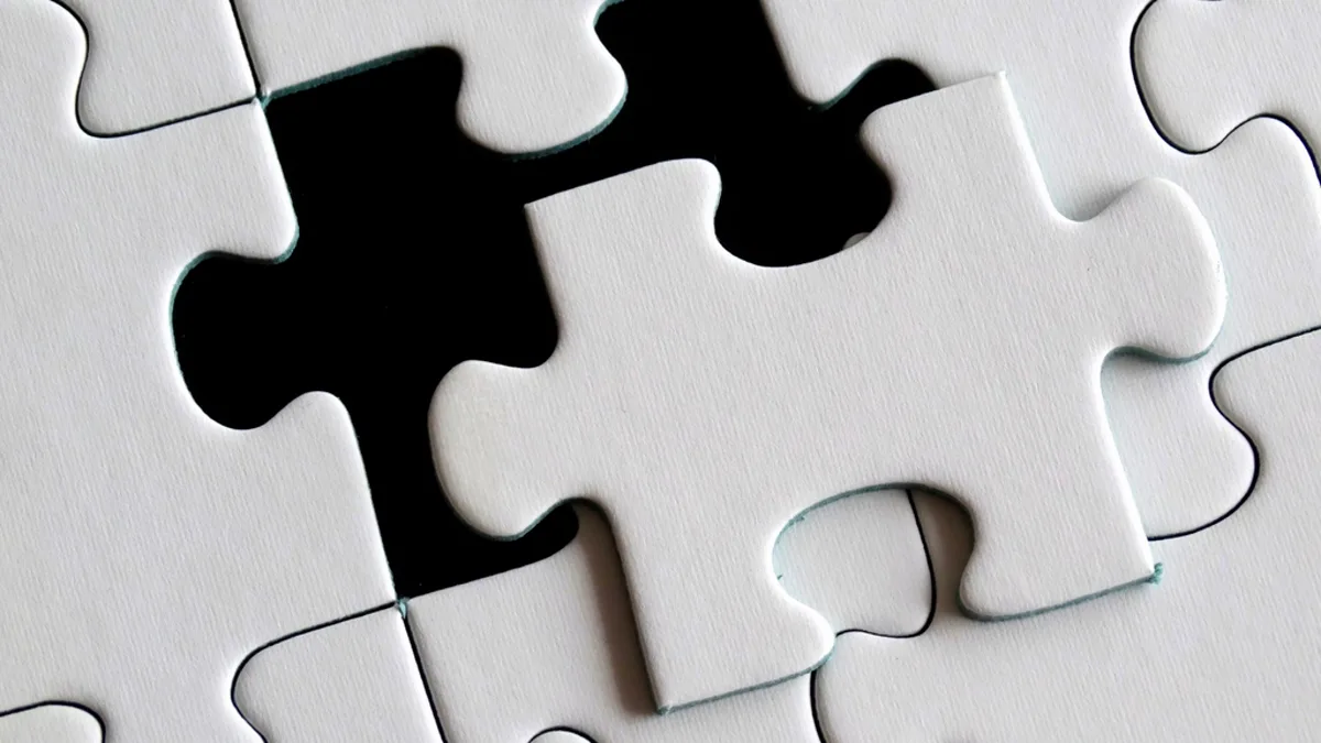 White puzzle piece resting above a nearly completed puzzle