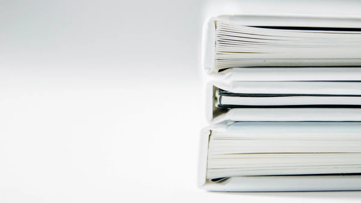 A tall stack of thick folders against a white background