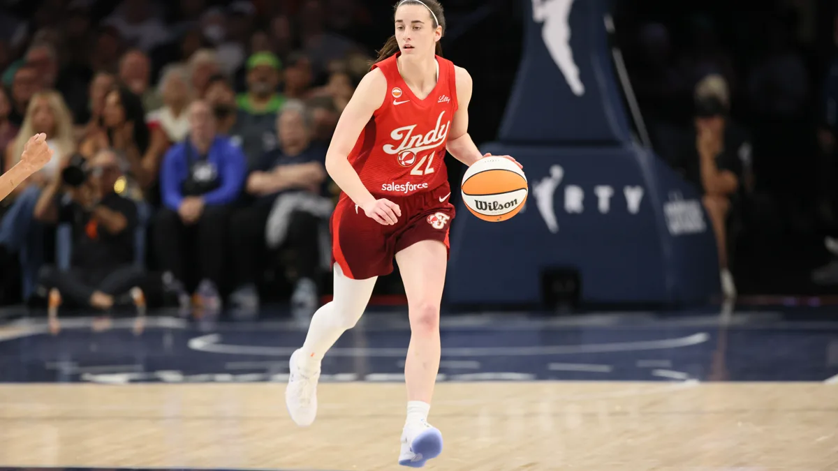 Caitlin Clark dribbling up the court in a red Indiana Fever uniform during a 2026 WNBA game