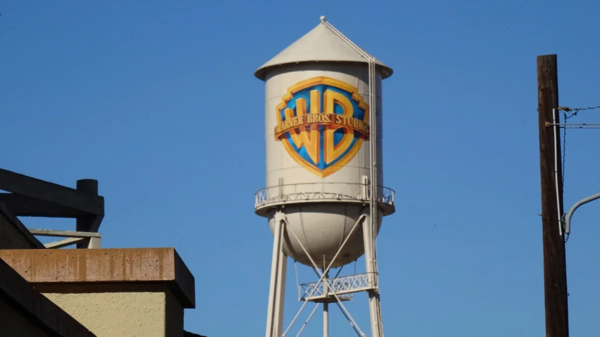 The Warner Bros. Studios water tower with the WB shield logo against a blue sky in Burbank, California