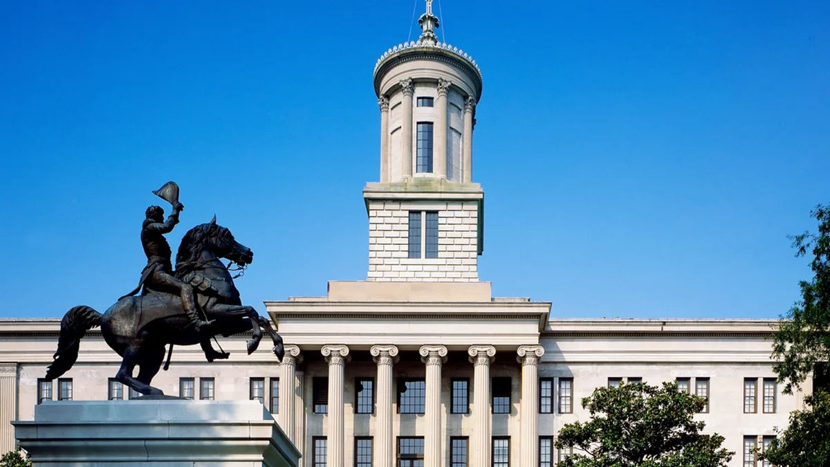 The Tennessee State Capitol in Nashville under a clear blue sky, with the Andrew Jackson equestrian statue in the foreground