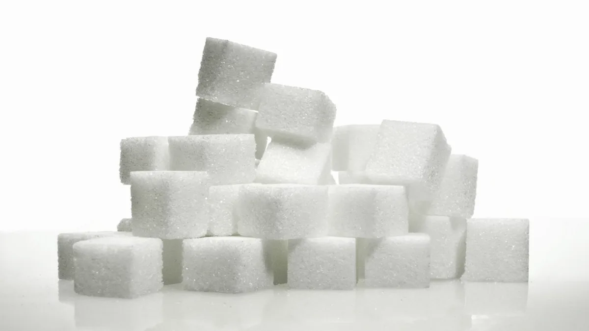 A stack of white sugar cubes on a plain white surface