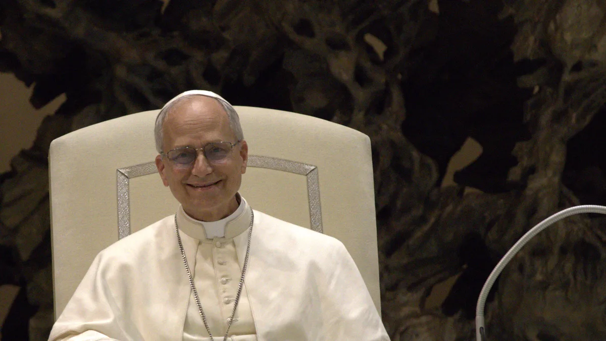 Pope Leo XIV seated in a white chair during an audience at the Vatican