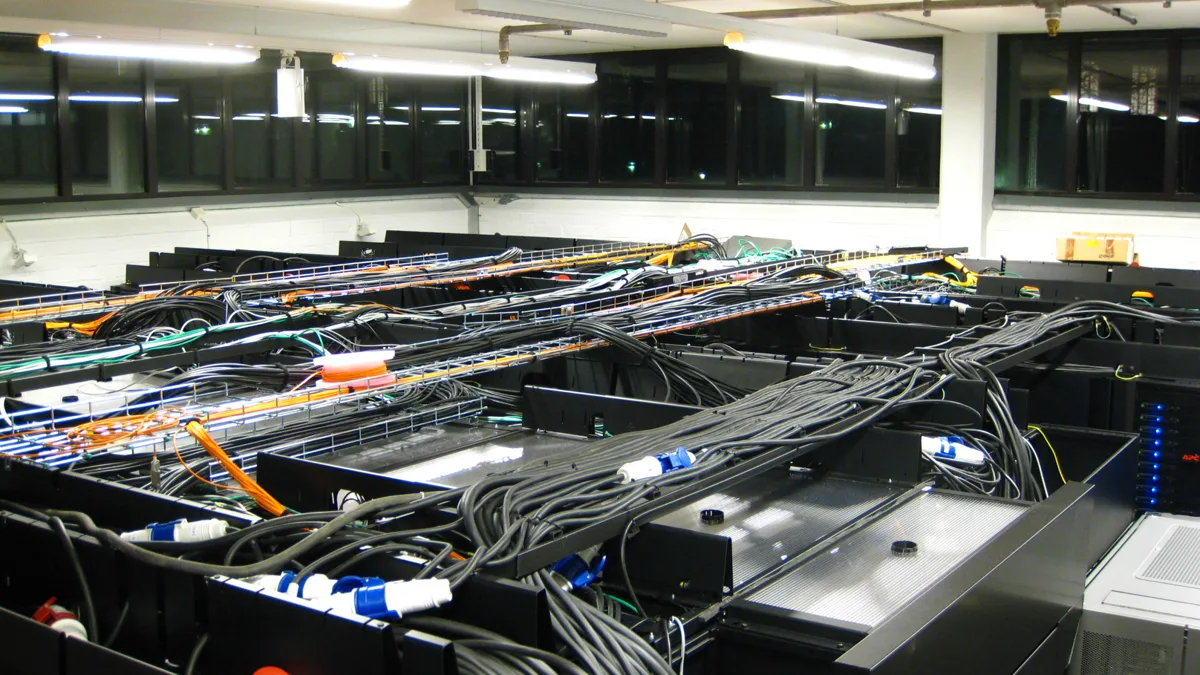 Rows of black server racks and bundled power and network cables in a data center room