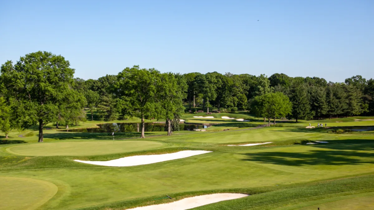 A golf course fairway with bunkers and greens under a clear summer sky