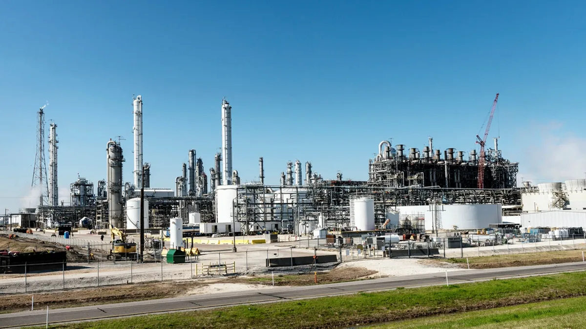 Distillation towers and storage tanks at an oil refinery under a clear sky