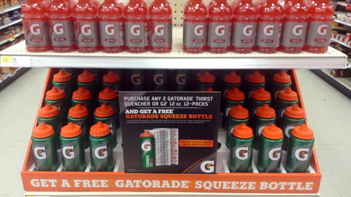 Gatorade bottles lined up on a supermarket shelf above a promotional display