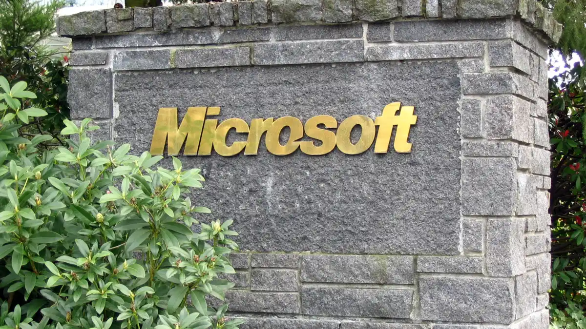 A Microsoft sign in gold lettering mounted on a stone wall at a company entrance