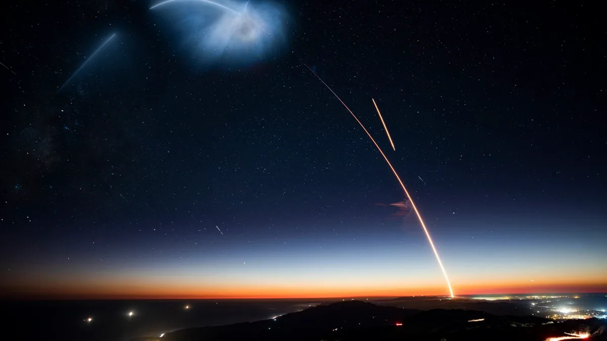 A SpaceX rocket arcs across a night sky above the coastline after a launch