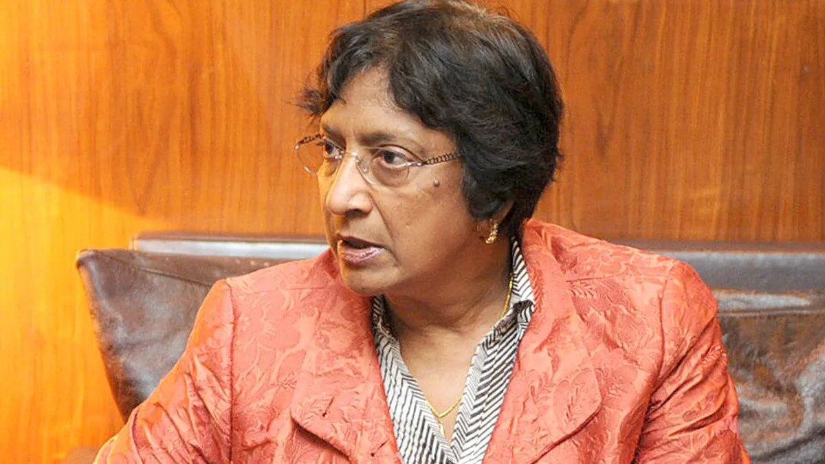 Navi Pillay seated in an orange jacket holding a document
