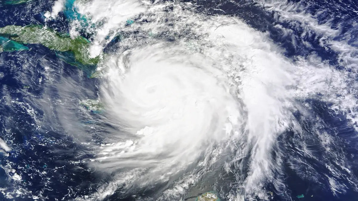 Satellite view of a hurricane with a visible eye spinning over open water near land