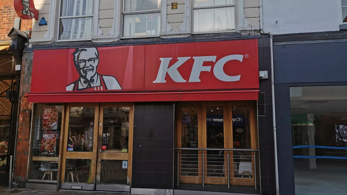 The red storefront and sign of a KFC restaurant on a city street