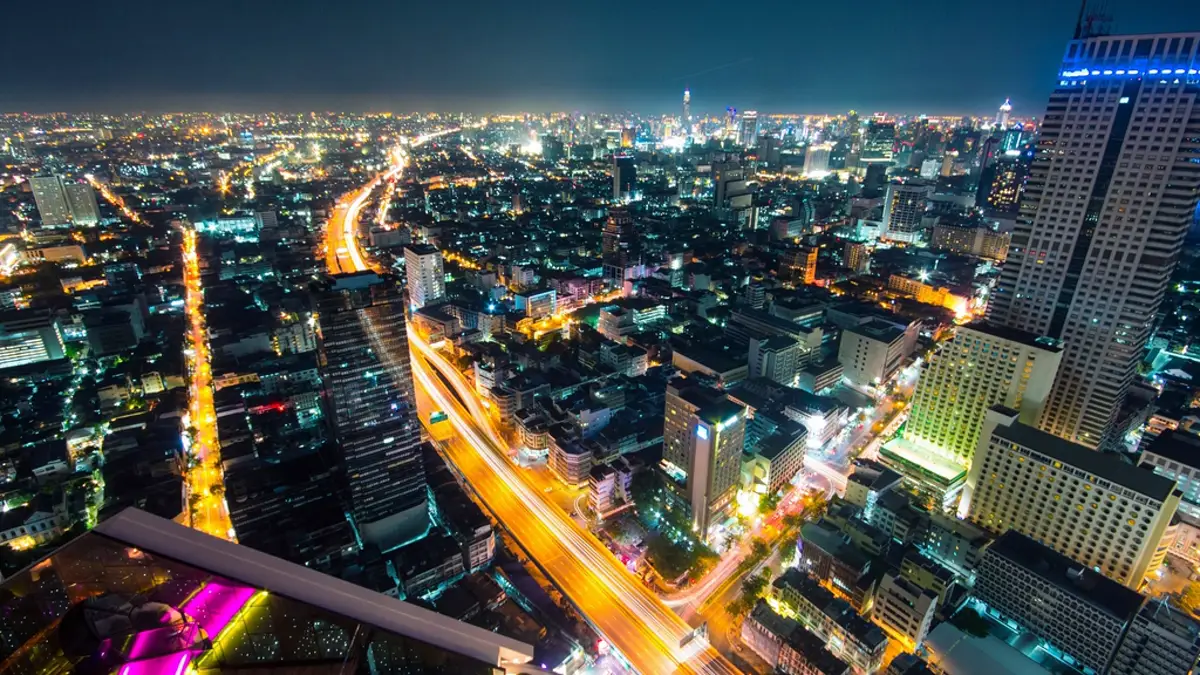 Aerial night view of the Bangkok skyline with traffic light trails along an expressway