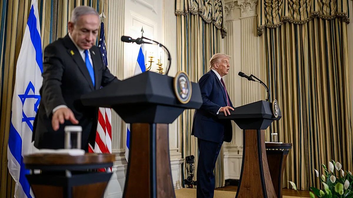 Benjamin Netanyahu and Donald Trump stand at separate podiums beside Israeli and US flags at a White House press conference