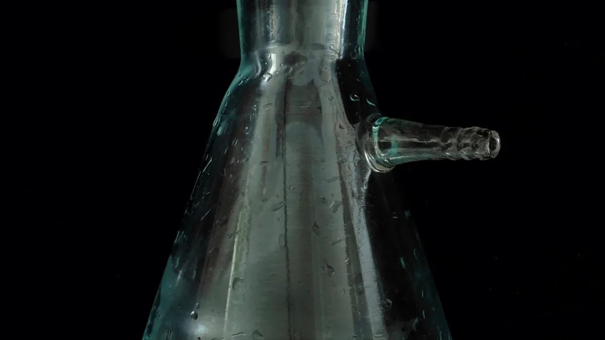 A glass laboratory flask photographed against a black background