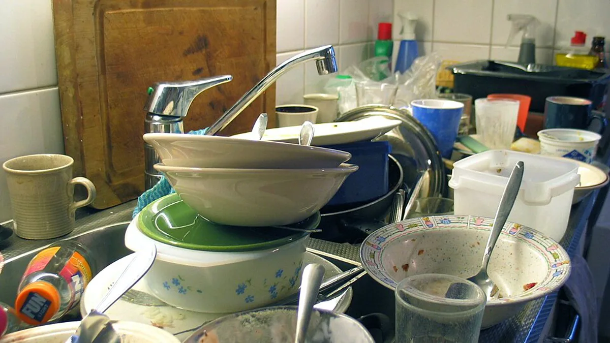 A kitchen sink piled high with unwashed dishes, bowls and glasses