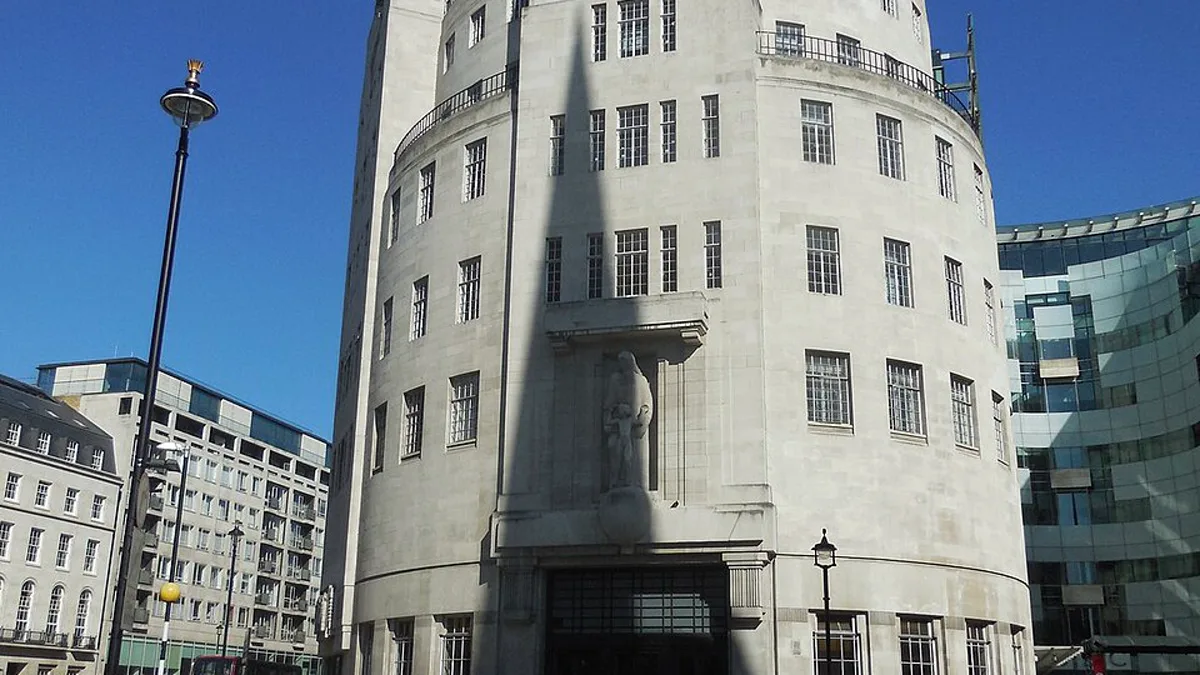 The curved stone facade of BBC Broadcasting House in central London under a clear blue sky